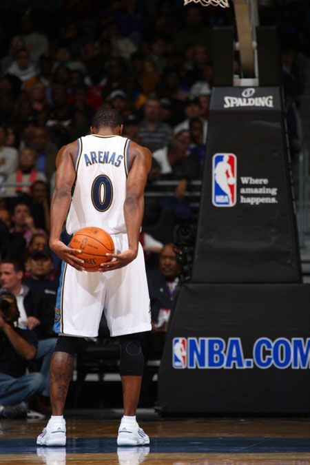 a man holding a basketball on top of a basketball court in front of a crowd