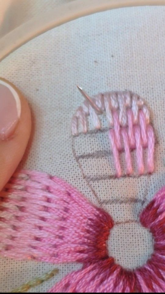 someone is stitching something on a piece of fabric with pink thread and scissors in the background