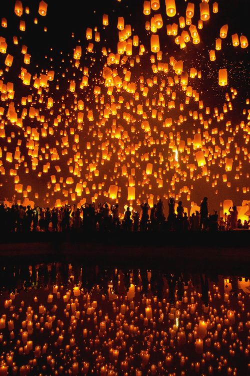 many lit up lanterns floating in the air