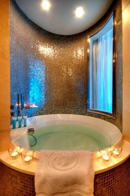 a bathroom with a large jacuzzi tub next to a window and candles on the counter