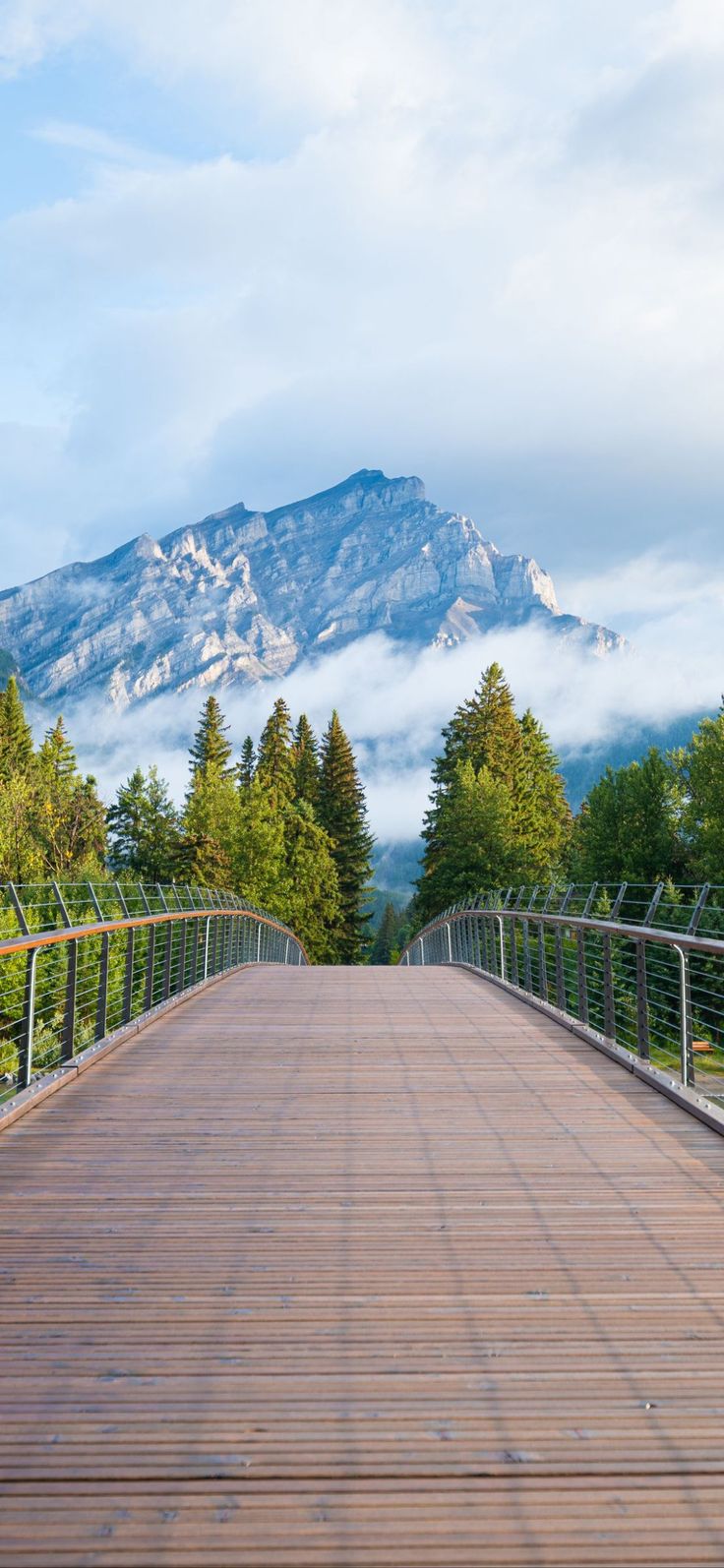 a wooden bridge with mountains in the background