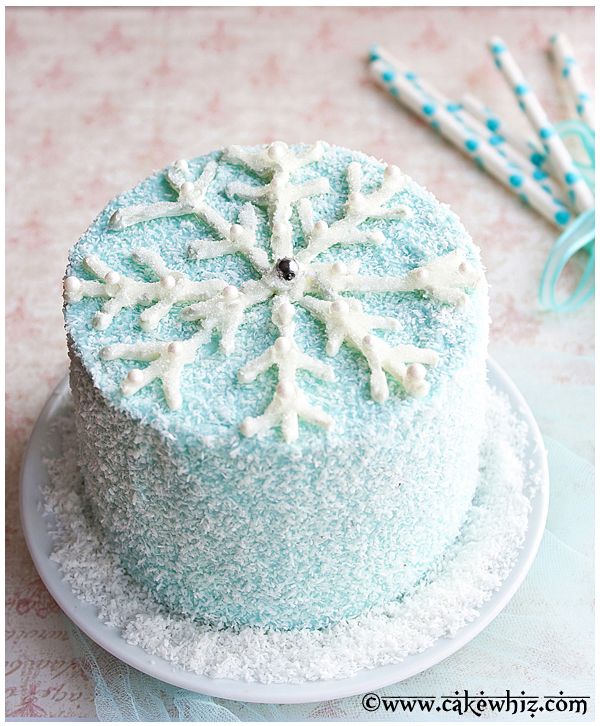 the cake is decorated with snowflakes and has two straws on top of it