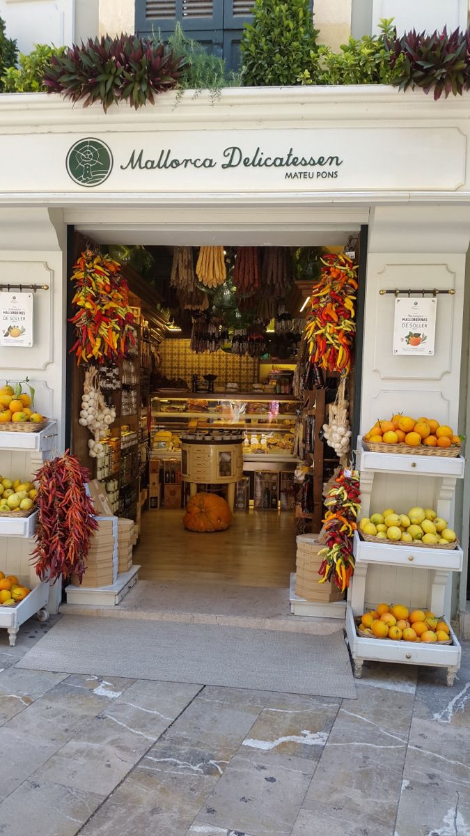 the entrance to a fruit and vegetable shop with lots of oranges on display in front