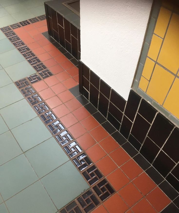 an orange and black tiled floor next to a white wall in a room with yellow walls