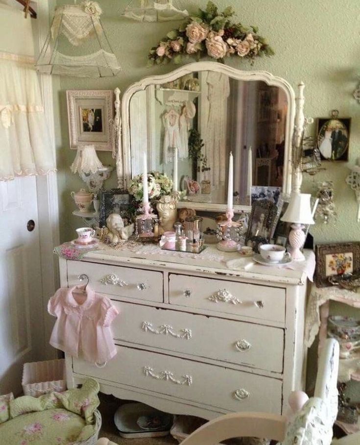 a white dresser sitting in a bedroom next to a chair and table with flowers on it