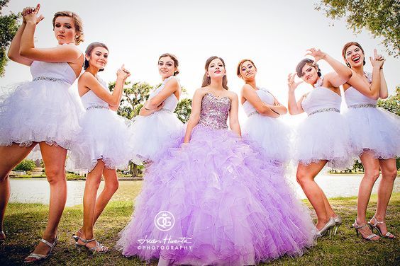 a group of young women dressed in dresses posing for the camera with their hands up