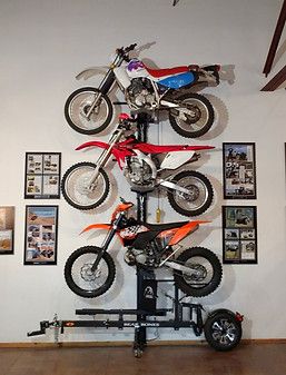 there is a motorcycle on top of a bike stand in the room with pictures around it