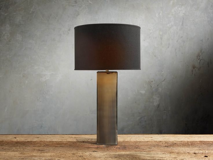 a table lamp with a black shade on it sitting on top of a wooden table