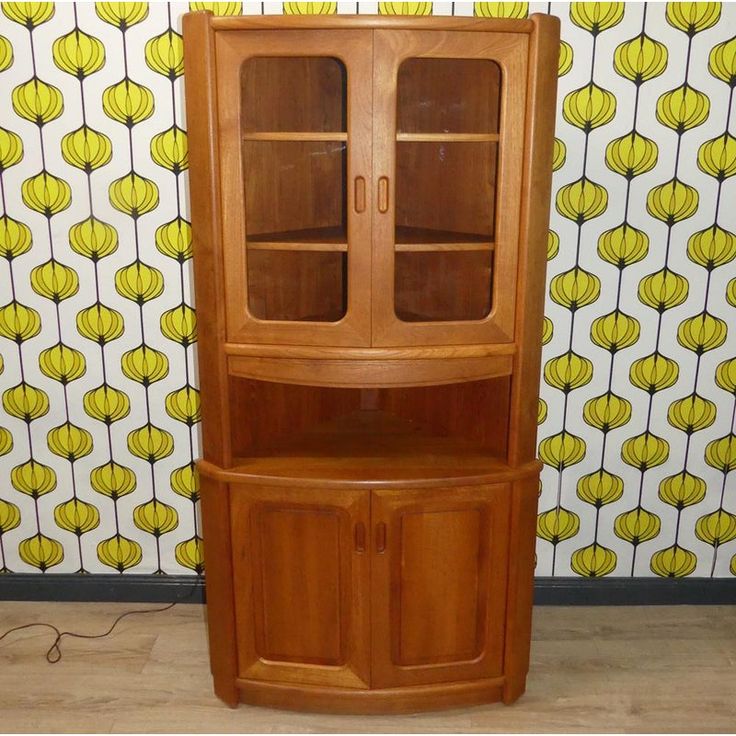 a wooden china cabinet sitting in front of a wall with yellow flowers on the background