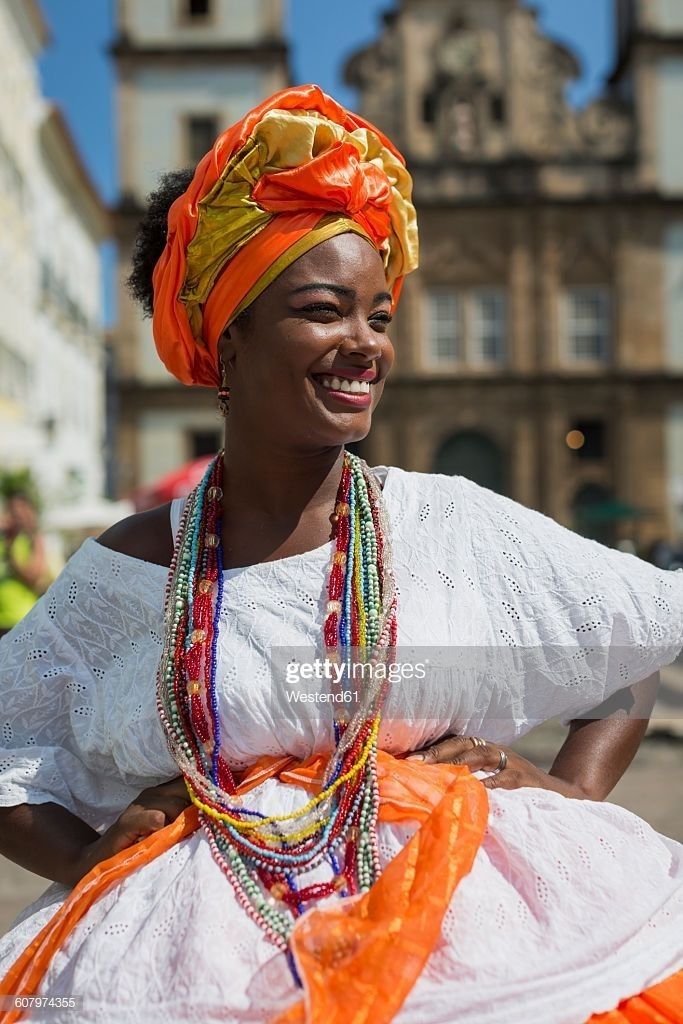 a woman in an orange and white dress smiles at the camera while walking down a street - stock photo