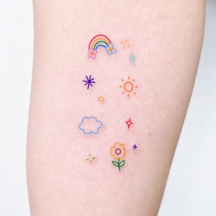 a woman's thigh with colorful tattoos on her legs and rainbows, stars, clouds, sunflowers and flowers