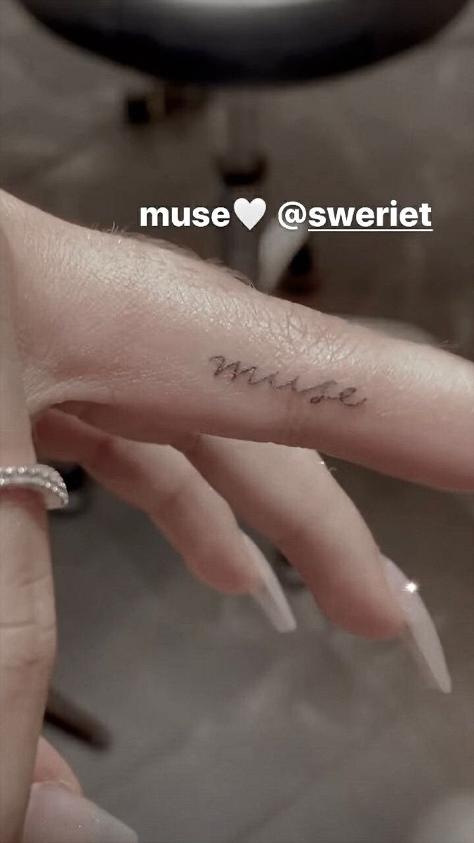 a woman's hand with a small tattoo on the middle finger that says, i love you