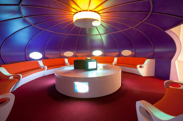 a room with several chairs and lights on the ceiling, along with a round table