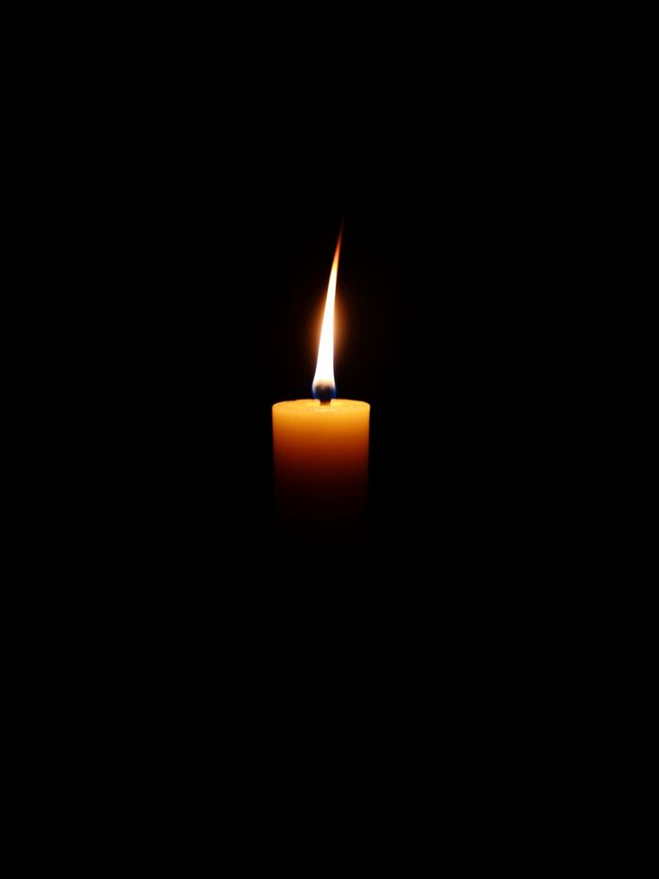 a lit candle in the dark with only one light on it's side,