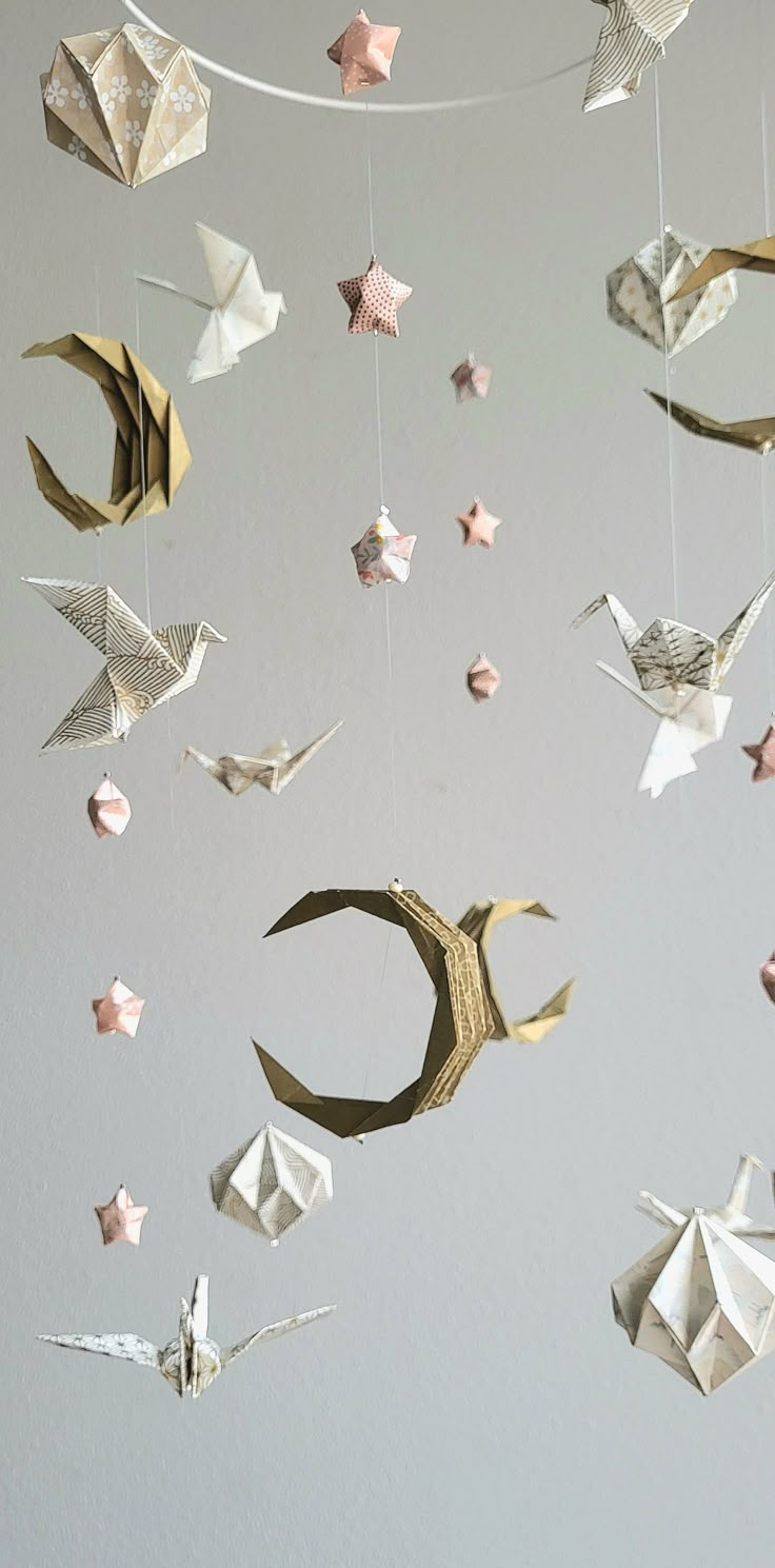 an origami mobile hanging from a string with stars and crescents on it