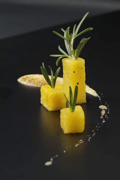 pineapple cubes with rosemary garnish on a black surface