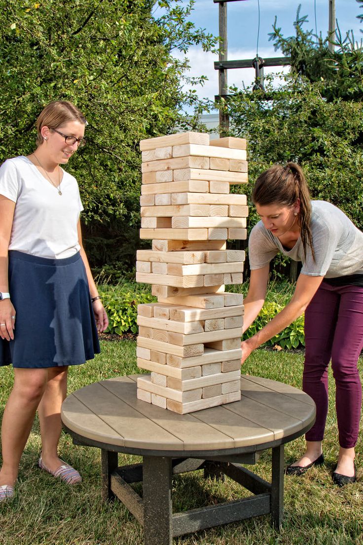 two women playing with a giant wooden block tower