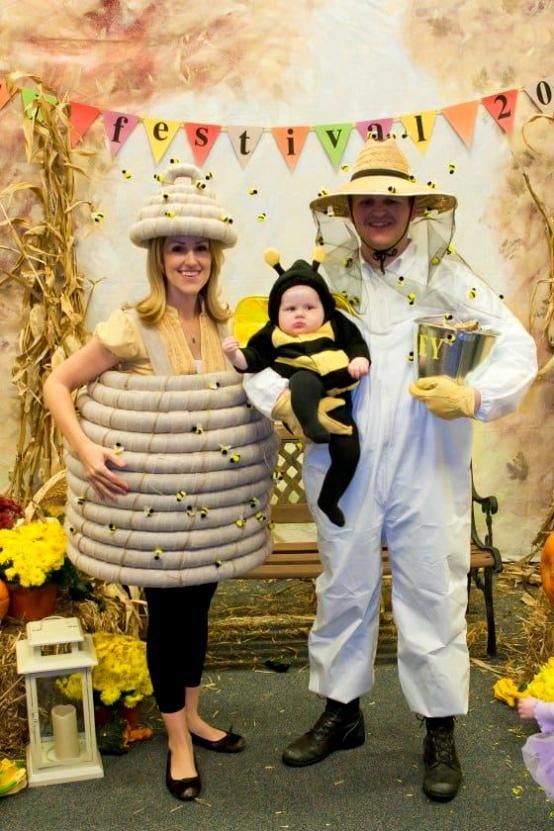 a man and woman in bee costumes holding a baby