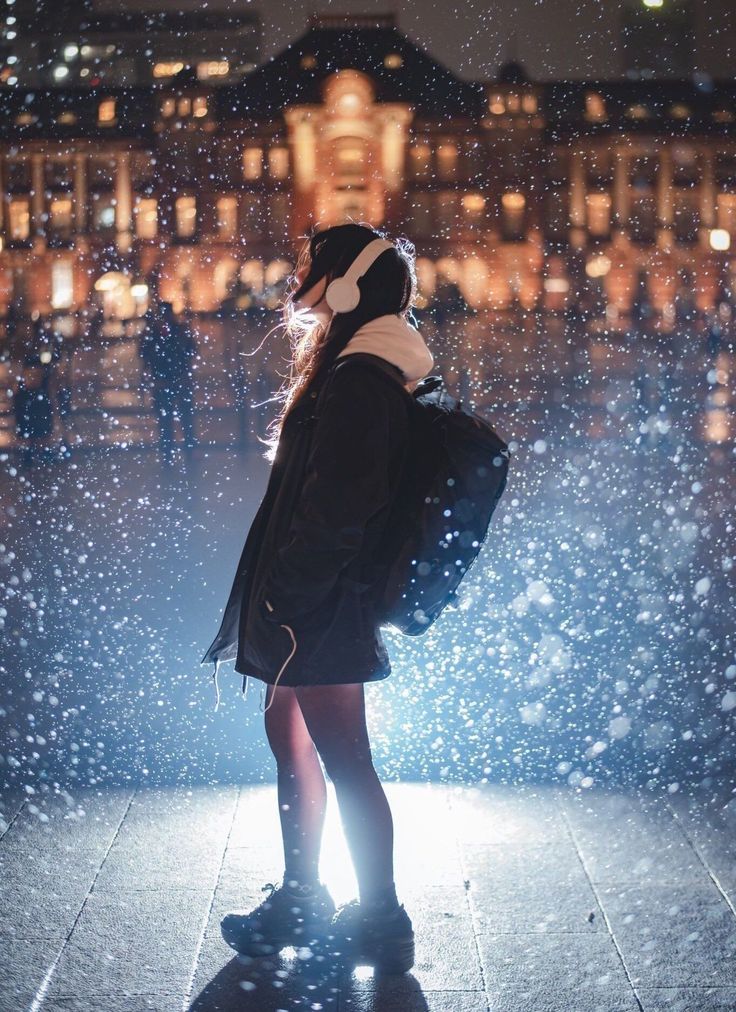 a woman standing in the rain with her back to the camera