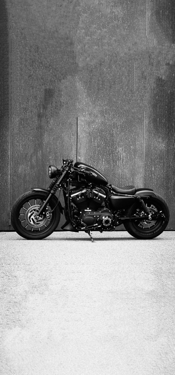 a black motorcycle is parked in front of a gray wall and cement flooring area