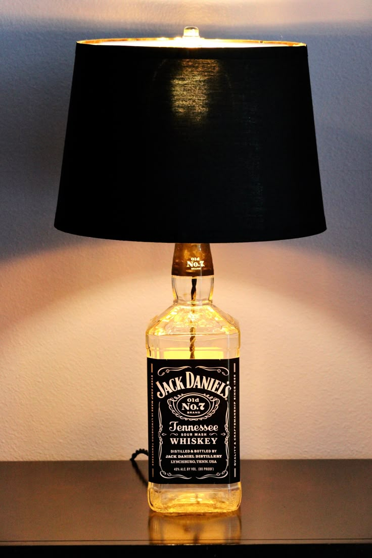 a lamp that is on top of a table with a bottle in front of it