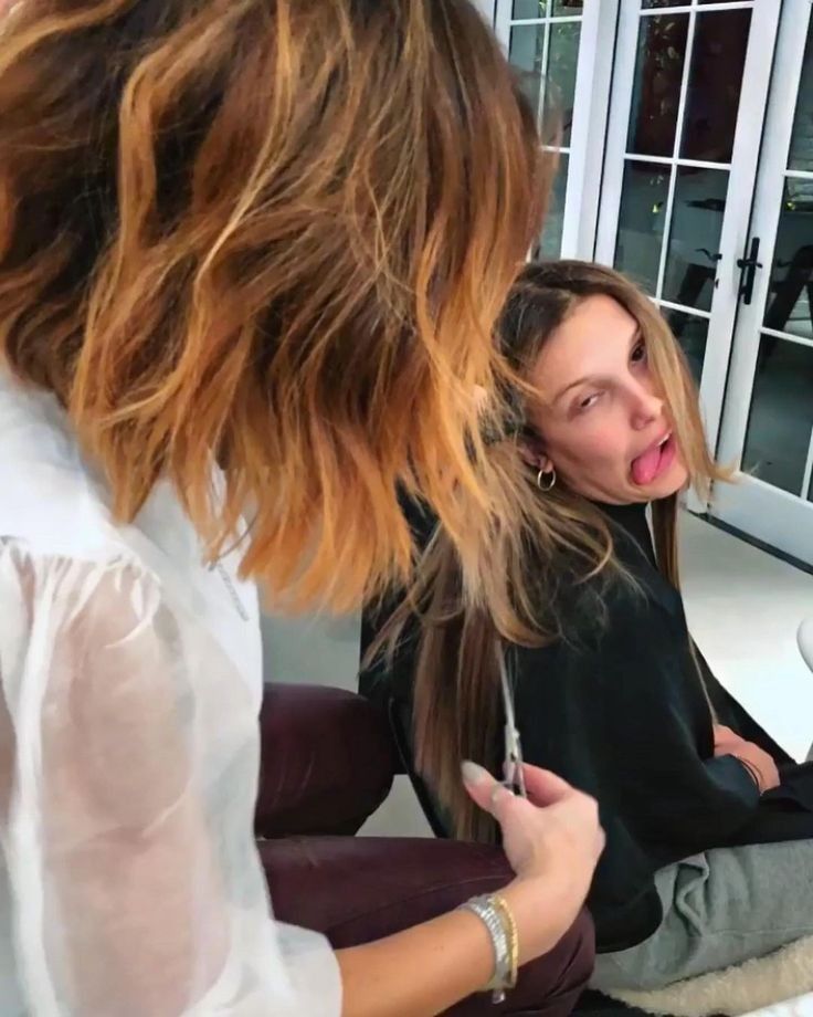 a woman is getting her hair styled by another woman