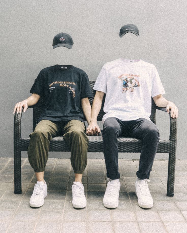 two people sitting on a bench with hats on their heads and one person wearing a t - shirt