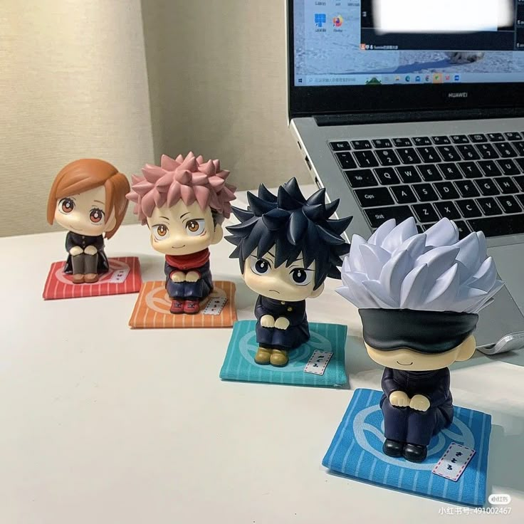 three anime figurines are sitting in front of a laptop