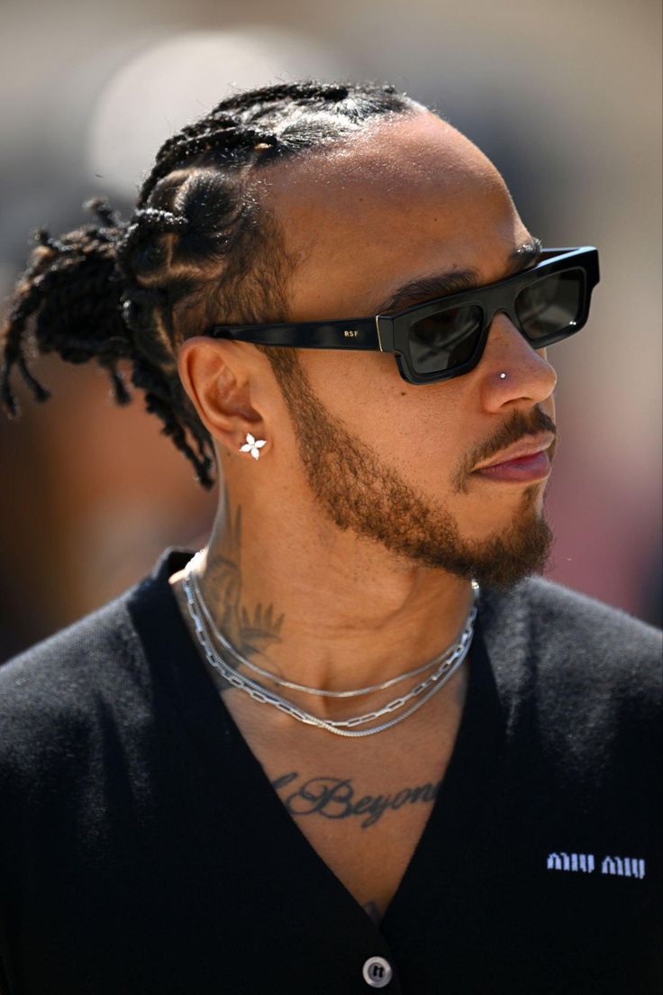 a close up of a person wearing sunglasses and a chain around his neck with tattoos on it