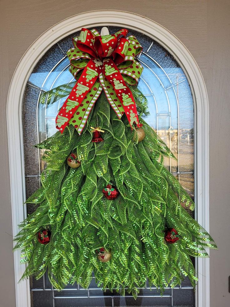 a christmas tree made out of green leaves and red bows on the front door with an instagram message below