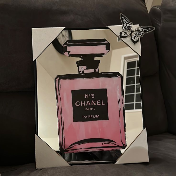 a mirror with a pink perfume bottle on it and a butterfly sitting on top of it