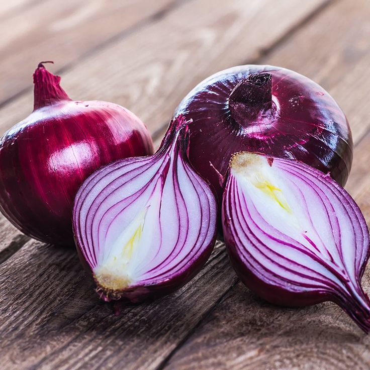 two onions on a wooden table with one cut in half