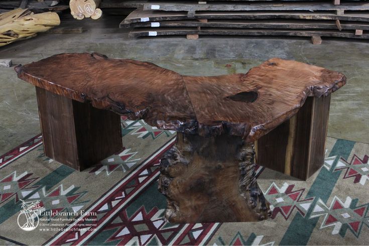 a wooden bench sitting on top of a rug next to stacks of wood planks