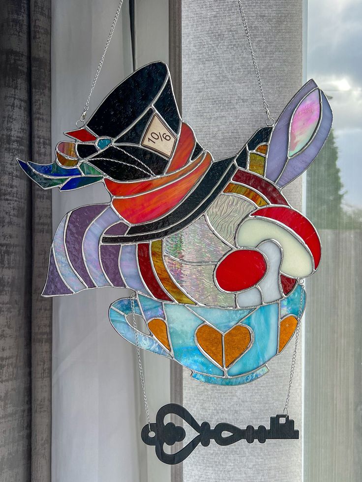 a stained glass bird hanging from the side of a window