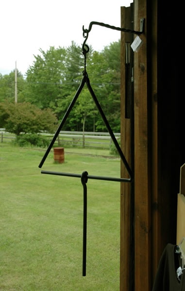 an open door with a wind chime hanging from it's side in front of a grassy field