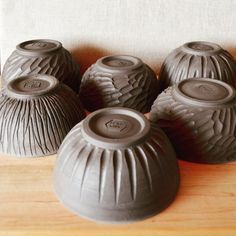 four ceramic vases sitting on top of a wooden table