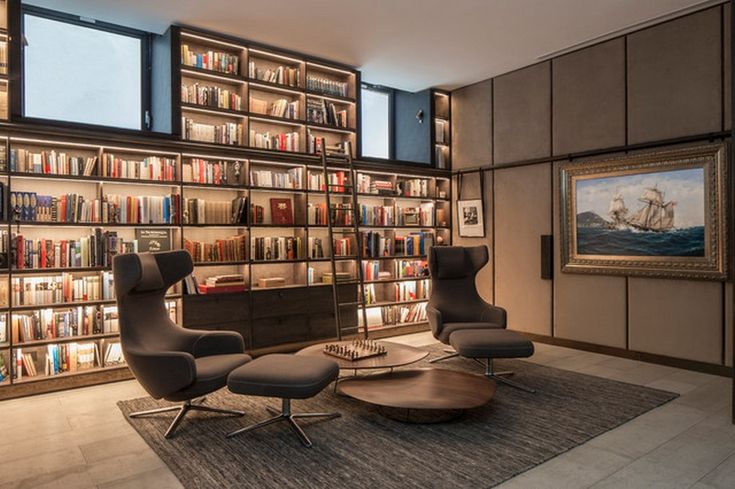 a living room filled with lots of furniture and bookshelves next to a painting