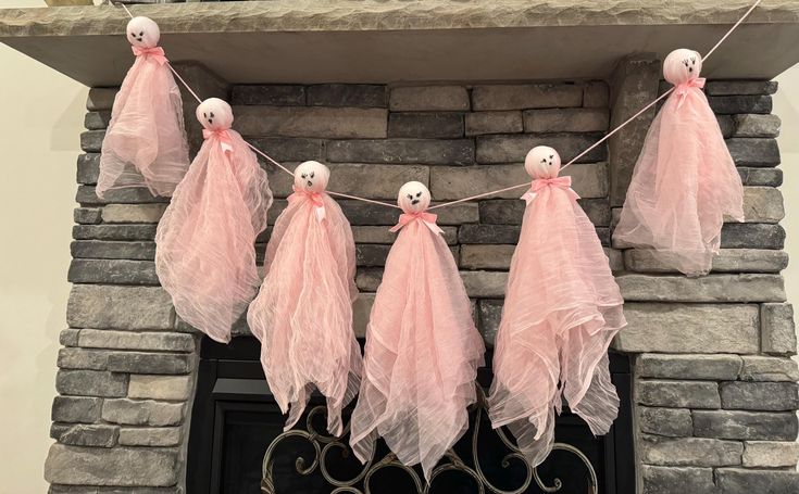 halloween decorations hanging on a mantle in front of a fire place with ghost heads and pink tulle