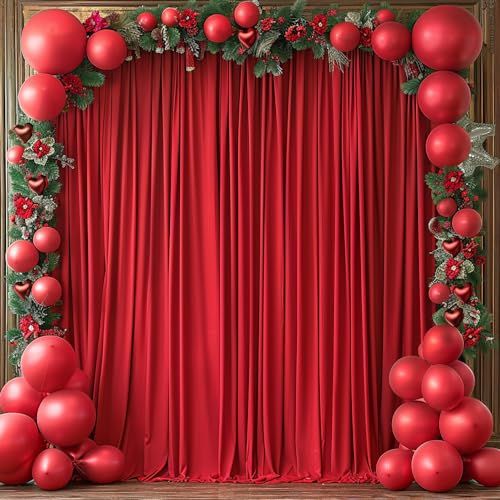 a red curtain with christmas decorations on it and some balls in the middle, along with greenery