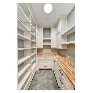 an empty walk - in closet with white cabinets and wood counter tops on the floor