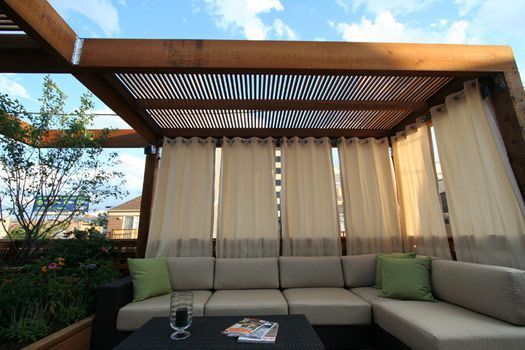 an outdoor living area with couches and curtains