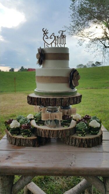 a wedding cake sitting on top of a wooden table in the middle of a field