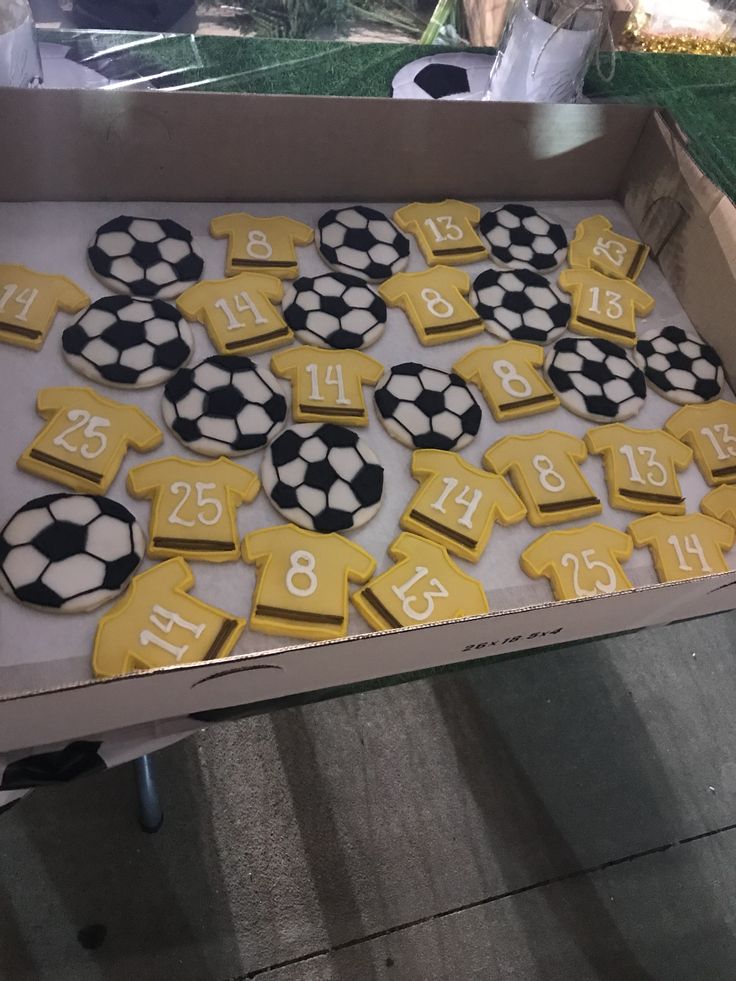 a table topped with lots of cookies covered in yellow and black frosted soccer numbers