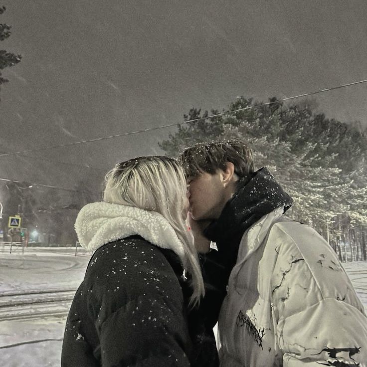 a man and woman kissing in the snow