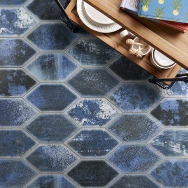 a wooden table topped with plates and bowls on top of a blue tiled floor next to a cutting board