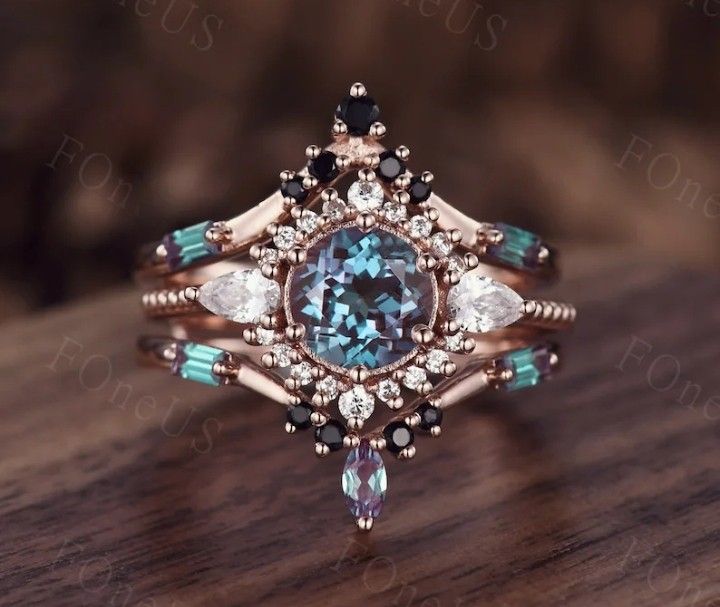 a fancy ring with an aqua blue stone surrounded by white and black diamonds on a wooden surface