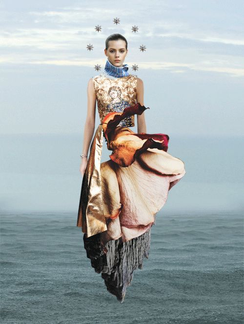 a woman is walking on the beach in a dress made out of flowers and leaves