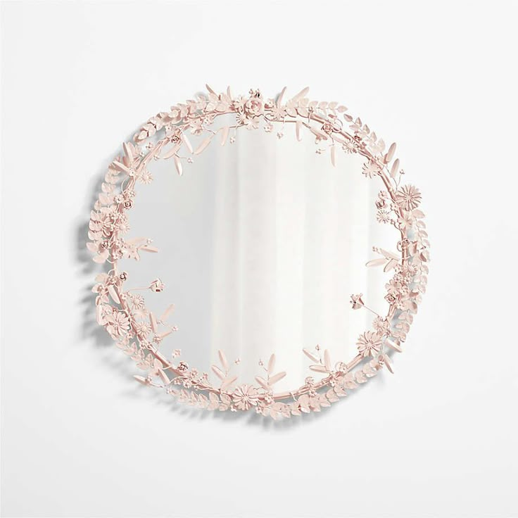 a round mirror with pink flowers on the side and a white wall in the background