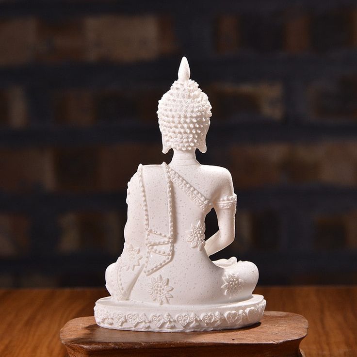 a white buddha statue sitting on top of a wooden table