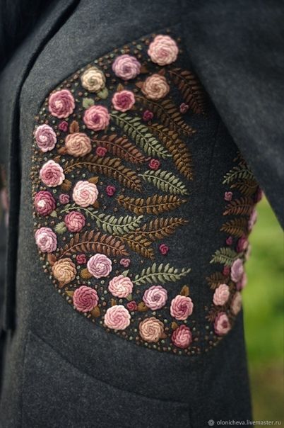 the back of a woman's black jacket with pink and green flowers on it